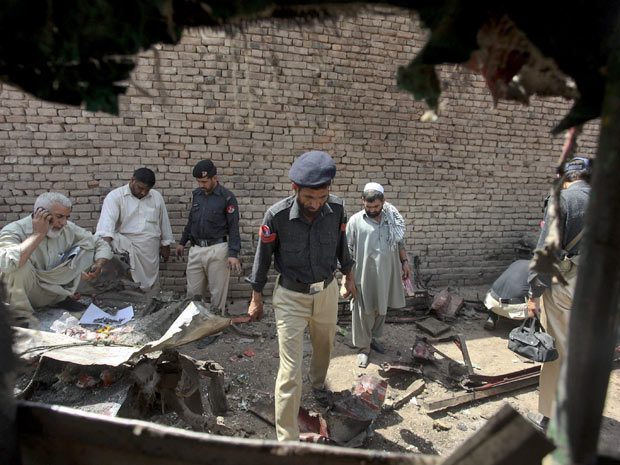 Policiais paquistaneses examinam local onde bomba explodiu. (Foto: Mohammad Sajjad / AP Photo)