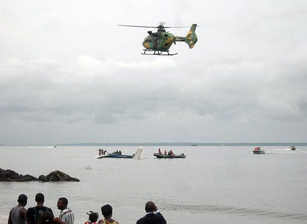 Pessoas observam avião da DHL acidentado próximo a praia de Libreville, no Gabão (Foto: AFP)