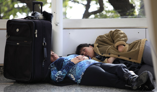 Duas passageiras descansam no chão do Aeroporto Jorge Newbery, em Buenos Aires, que teve os voos cancelados ou suspensos nesta quinta-feira (9) (Foto: Natacha Pisarenko / AP)