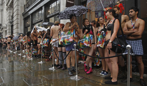 Clientes em roupas íntimas aguardam sob chuva a abertura de loja em Londres, nesta quinta (16) (Foto: Luke MacGregor / Reuters)