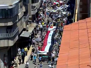 Protestantes carregam bandeira da Síria a 160 km de Damasco, na Síria. (Foto: AFP Photo / YouTube)