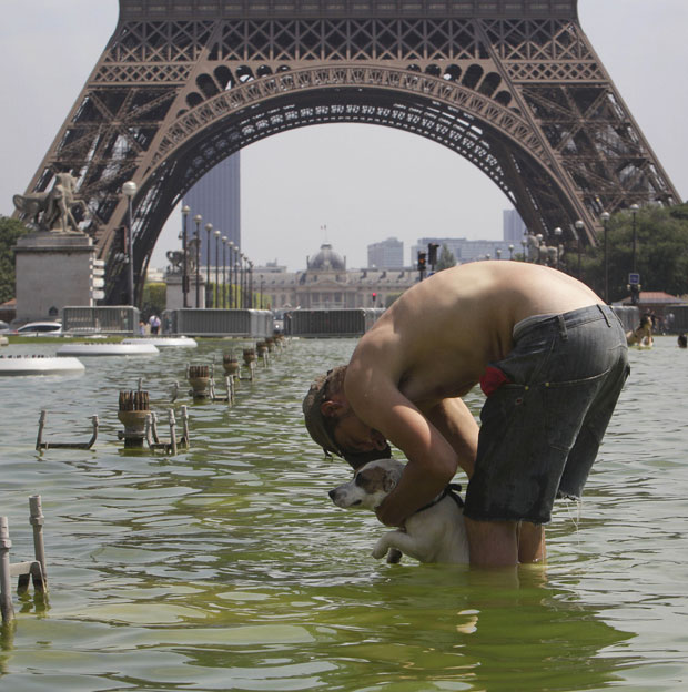 Em Paris, homem aproveitou para refrescar seu cachorro na fonte de Trocadero, próximo à Torre Eiffel. Na cidade, o calor chegou a 35° Celsius (Foto: AP)