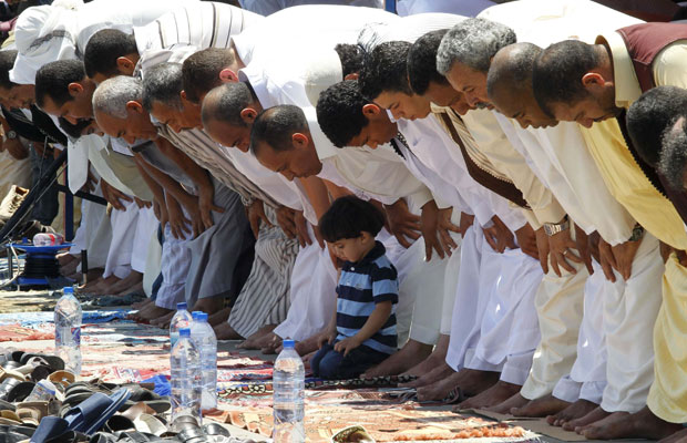 Homens e menino líbios oram na última sexta-feira (9), em Trípoli (Foto: Louafi Larbi/Reuters)