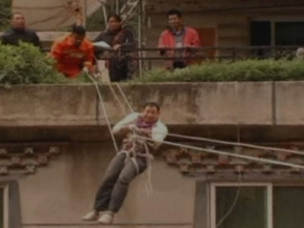 Homem precisou usar cordas para conseguir sair de um edifício que foi ilhado pela enchente (Foto: BBC)