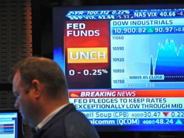 Operador trabalha em frente à TV que noticia o anúncio do Fed nesta terça-feira (9), na Bolsa de Nova York. (Foto: Stan Honda/AFP)