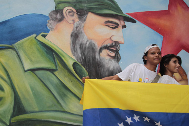 Casal posa diante de painel com pintura de Fidel, durante comemorações do 85º aniversário do líder cubano  (Foto: Oswaldo Rivas / Reuters)