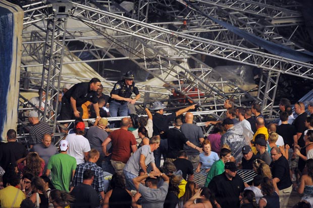Policiais e voluntários tentam erguer ferragens após queda de palco em Indiana, nos EUA (Foto: AP)
