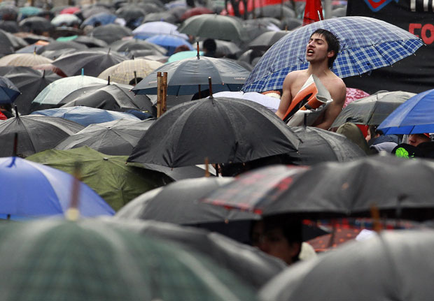 Mesmo com guarda-chuvas, milhares de pessoas foram às ruas de Santiago (Foto: Reuters)