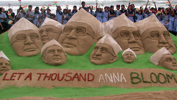 Criançs posam em frente à escultura de Anna Hazare feita pelo artista Sudarshan Patnaik, em uma praia de Puri, na Índia (Foto: Reuters)