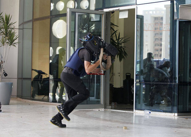 Cinegrafista corre para dentro do Hotel Corinthia, em Trípoli, após ouvir o início de uma troca de tiros (Foto: Louafi Larbi/Reuters)