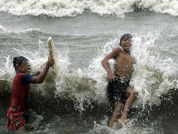 Crianças brincam no mar agitado após passagem do tufão Nanmadol. (Foto: Pat Roque / AP Photo)