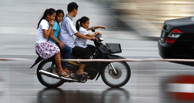 Motociclista anda com moto superlotada Phnom Penh. (Foto: Heng Sinith/AP)