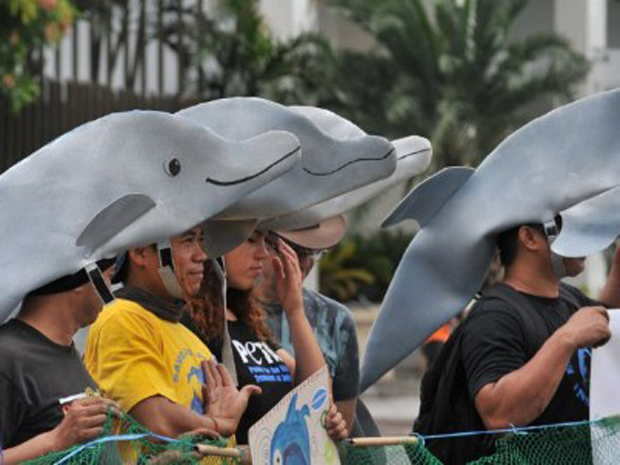 Ativistas com capacetes no formato de golfinhos realizam protesto nas Filipinas (Foto: Ted Aljibe/AFP)