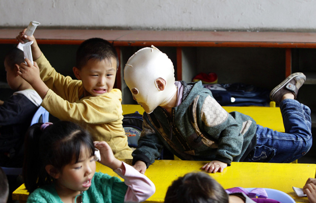 Wang Gengxiang na escola, interagindo com colegas (Foto: Jason Lee / Reuters)