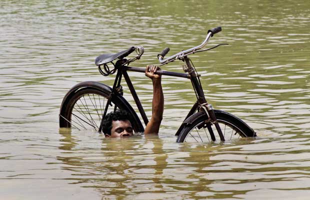 Homem resgata sua bicicleta durante enchente próximo à vila de Megha, a 55 km de Bhubaneswar, na Índia, neste domingo (11). As fortes chuvas que atingem 14 distritos do estado de Orissa afetou mais de 700 mil pessoas. O governo iniciou uma 'operação de guerra' para resgatar moradores (Foto: Biswaranjan Rout/AP)
