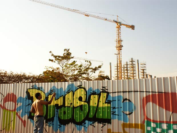 Grafiteiro pinta nesta quinta-feira (15) painel em um dos trechos do tapume que circunda as Obars do Estádio Nacional de Brasília (Foto: Vianey Bentes/TV Globo)