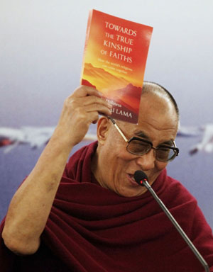 O líder tibetano brinca exibindo seu novo livro (Foto: Nacho Doce/Reuters)