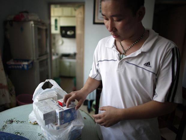 Cao Gong mostra os remédios que seu filho Cao Chen terá que tomar por causa da intoxicação (Foto: Reuters / Carlos Barria)