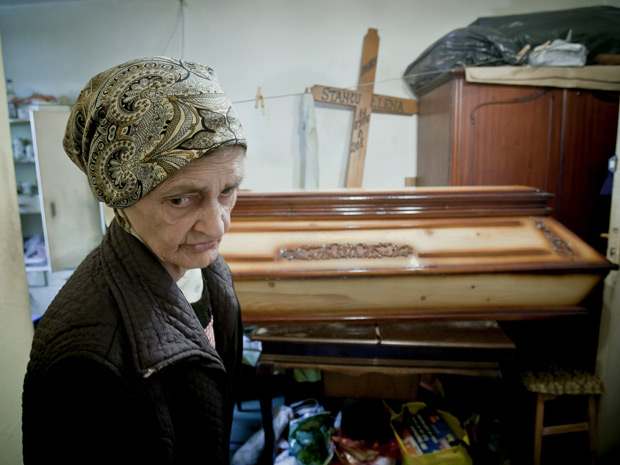 Elena Stancu, 75, guarda seu caixão no apartamento de um quarto onde mora, em uma região pobre da Romênia. Usou suas economias para comprá-lo. (Foto: Vadim Ghirda/AP)
