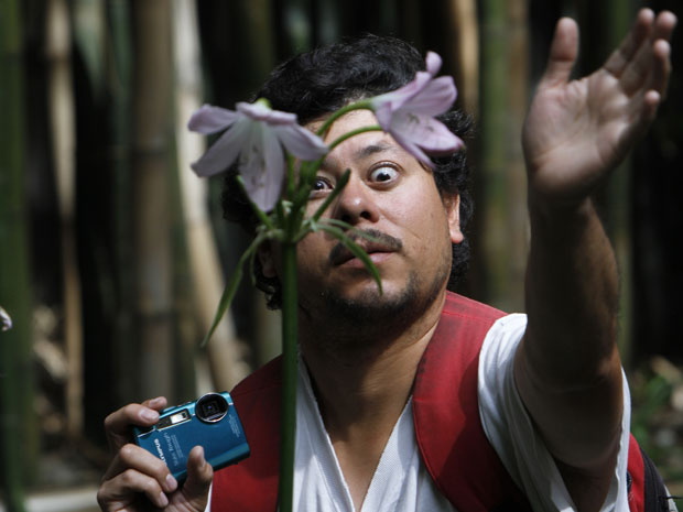 O deficiente visual Juan Antonio Hernandez tenta tocar uma flor para saber, pelo calor, de que lado a luz está batendo. Apesar de não conseguir enxergar, ele está aprendendo a tirar fotos na fundação Ojos que Sienten (Olhos que Sentem), na Cidade do México (Foto: Marco Ugarte/AP)