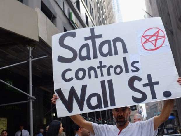 Cartaz afirma que Wall Street, o centro financeiro do país, é 'controlado pelo demônio'. No final de semana, cerca de 80 pessoas foram detidas durante os protestos. (Foto: AFP)