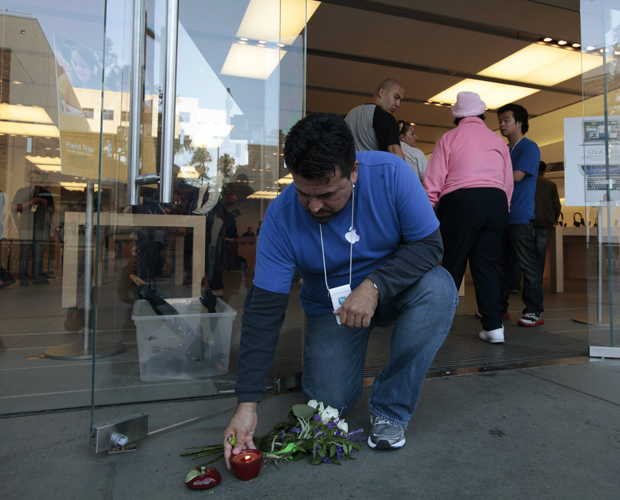 Funcionário da Apple acende uma vela em formato de maçã, colocada ao lado de uma loja da Apple em Santa Monica, na Califórnia  (Foto: Lucy Nicholson/Reuters)