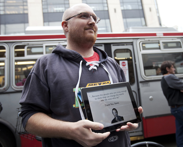 Funcionário da Apple segura um iPad mostrando mensagem em memória de Steve Jobs (Foto: Stephen Lam/Reuters)