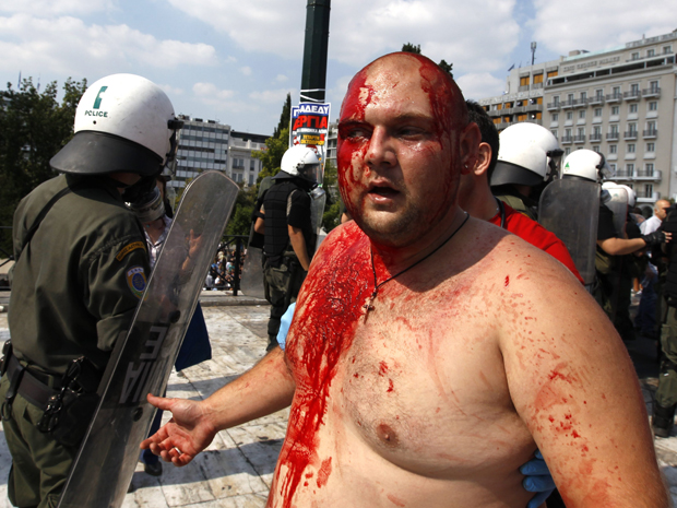 Homem coberto de sangue escapaou de ser linchado por um grupo de manifestantes da esquerda, que o acusou de ser fascista durante protesto em Atenas (Foto: Reuters)