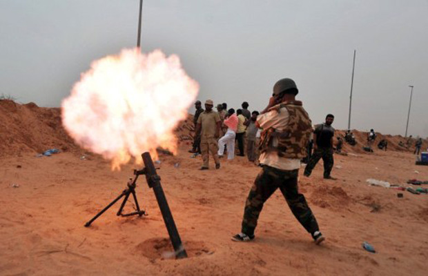 Combatente do Conselho Nacional de Transição lança morteiro contra tropas leais à Kadhafi, em Sirte (Foto: Aris Messinis / AFP)