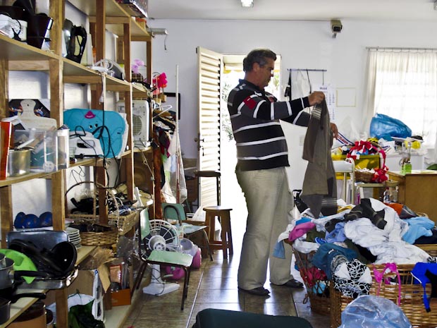 Homem organiza objetos para bazar. (Foto: Adriana Justi/G1 PR)
