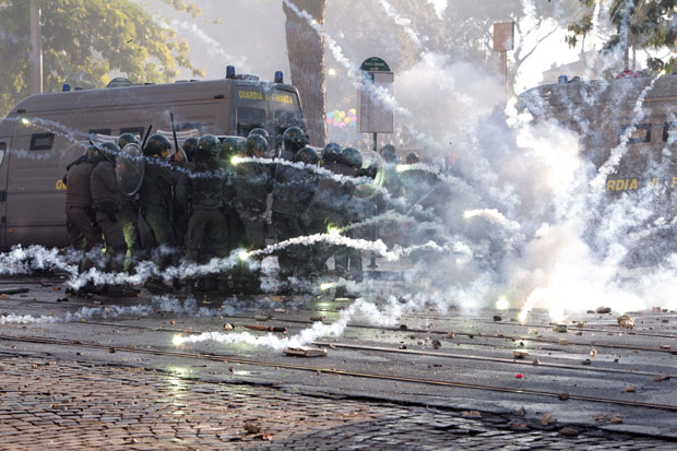 Policiais se protegem de artefato atirado por manifestantes (Foto: AP)