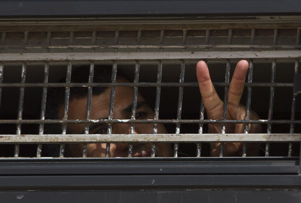 Prisioneiro faz sinal enquanto entra em ônibus para seguir até prisão antes de troca por soldado israelense (Foto: Ariel Schalit/AP)