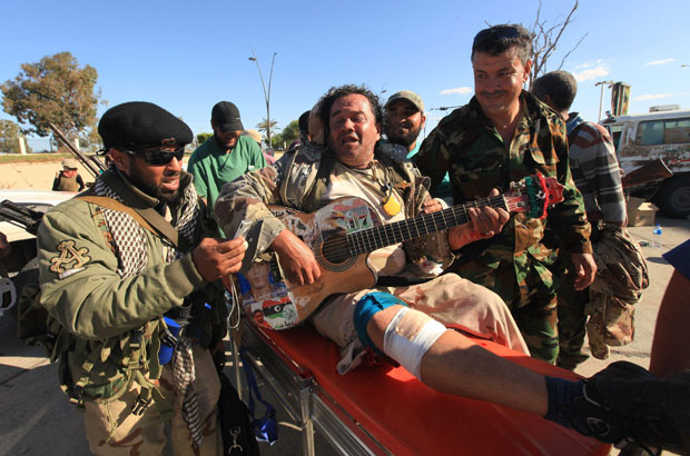 Ainda com o violão nos braços, homem recebe socorro em Sirte no sábado (15) (Foto: Esam Al-Fetori/Reuters)