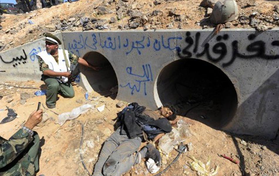 Combatente líbio mostra tubulação onde o ex-ditador Muammar Kadhafi teria sido capturado.