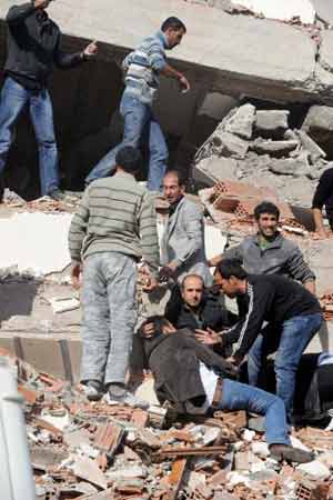 Ferido é socorrido entre escombros em Tabanli (Foto: AFP)