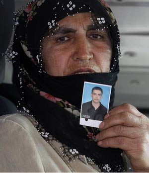 Turkan Ormanoglu, de 57 anos, mostra a foto do filho Tahir Ormanoglu, de 27, que ainda não foi encontrado em Ercis. (Foto: Burhan Ozbilici/AP)