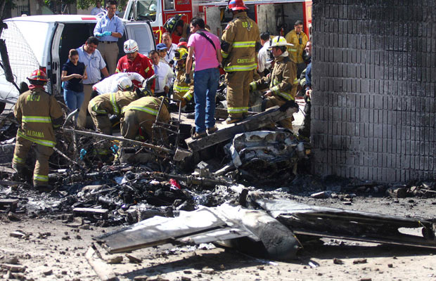 Bombeiros trabalham nos destroços de pequeno avião que caiu sobre uma oficina mecânica na área urbana da cidade mexicana de Tijuana nesta segunda-feira (31) (Foto: Reuters)
