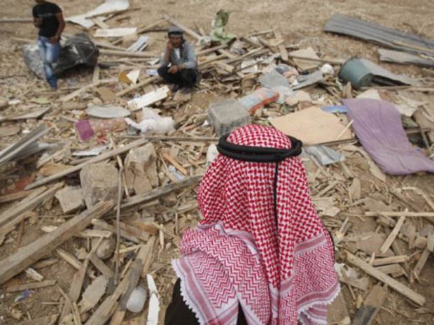 Beduínos palestinos entre pertences após suas barracas terem sido destruídas por tanques israelenses, em área deserta entre Jerusalém e Jericó, na Cisjordânia, nesta segunda-feira (31) (Foto: AFP)