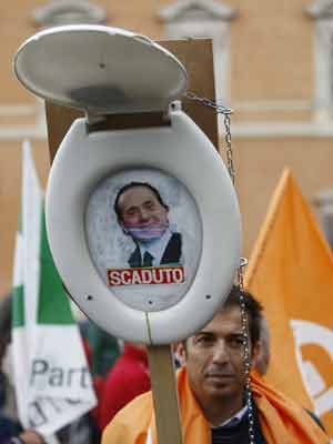 Manifestante com tampa de vaso com o rosto de Berlusconi e a expressão 'vencido' em ato neste sábado (5) em Roma (Foto: AP)