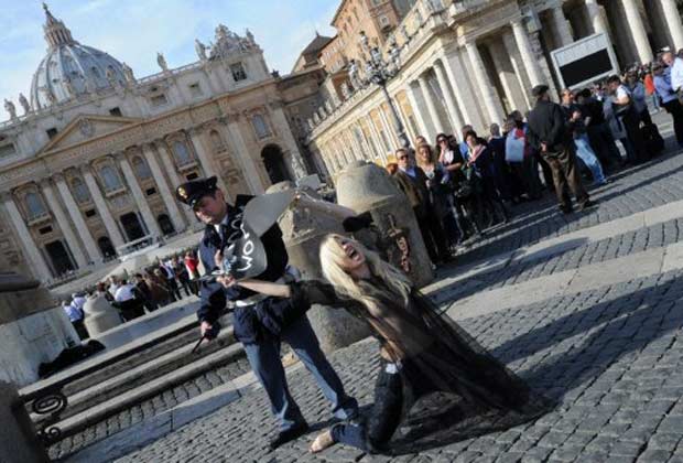 Policial arranca cartaz de ativista do movimento feminista ucraniano Femen durente protesto em frente à Basílica de São Pedro, no Vaticano, neste domingo (6). Ela protestou após a prece dominical do ângelus, feita pelo papa Bento XVI. O cartaz pedia 'libe (Foto: AFP)