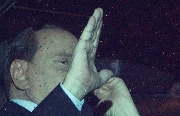 O premiê da Itália, Silvio Berlusconi, acena a jornalistas de dentro do carro após se reunir com o presidente Giorgio Napolitano na noite desta terça-feira (8) em Roma (Foto: AP)