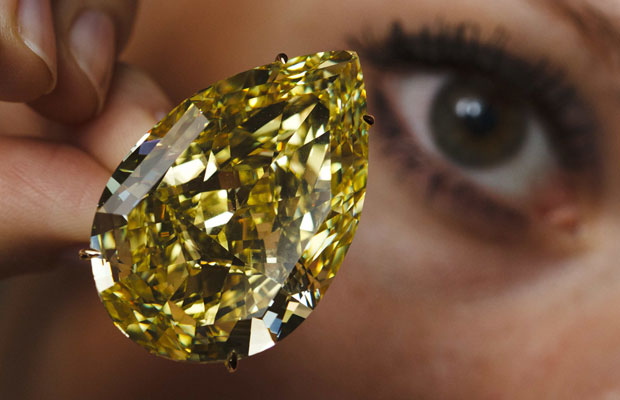 Modelo posa com o diamante 'Sun-Drop', de 110 quilates, em exibição em Genebra, na Suíça. A peça recebeu a maior graduação para um diamante amarelo e deve ser leiloada no dia 15 de novembro. Espera-se que seja vendida por US$ 11 a 15 milhões.  (Foto: Michael Buholzer/Reuters)