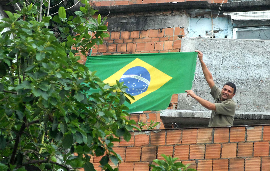 Morador comemora a ocupação estendendo uma bandeira do Brasil