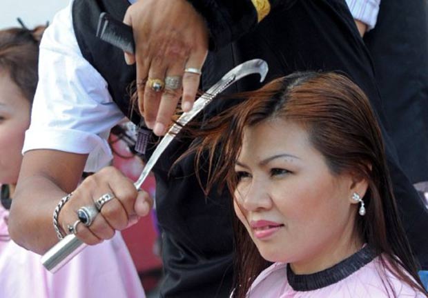 Um barbeiro foi visto usando uma foice para cortar o cabelo de clientes na quinta-feira (17) em Bangcoc, na Tailândia. (Foto: Pornchai KITTIWONGSAKUL/AFP)