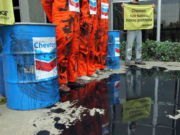 Os manifestantes vestiam roupas especiais e derramaram um líquido negro em frente ao prédio da empresa, que simulava um derramamento de óleo (Foto: Wilton Junior/AE)