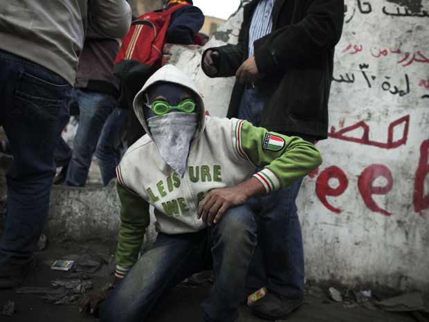 Manifestante protege-se do gás durante protesto nesta terça-feira (23) no centro do Cairo (Foto: AP)