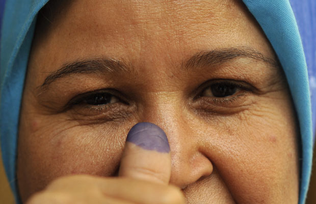 Eleitora egípcia mostra dedo sujo de tinta após votar nesta segunda-feira (28) no Cairo (Foto: AP)