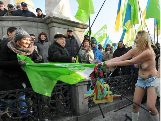 Uma das manifestantes arranca bandeira das mãos de militante do partido da oposição.  As ativistas acusam os organizadores de oferecem dinheiro para atrair pessoas à reunião.  (Foto: AFP)