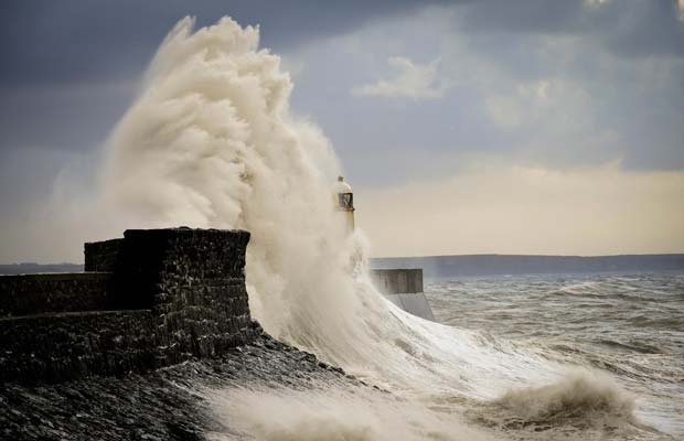 Fortes ondam chocam-se contra paredão do cais e envolve o farol em Porthcawl, no País de Gales, nesta terça-feira (13). Ventos de até 100 km/h atingiram várias regiões da Grã-Bretanha, e a previsão é de tempo ruim pelo resto da semana (Foto: AP/Ben Birchall/PA Wire)