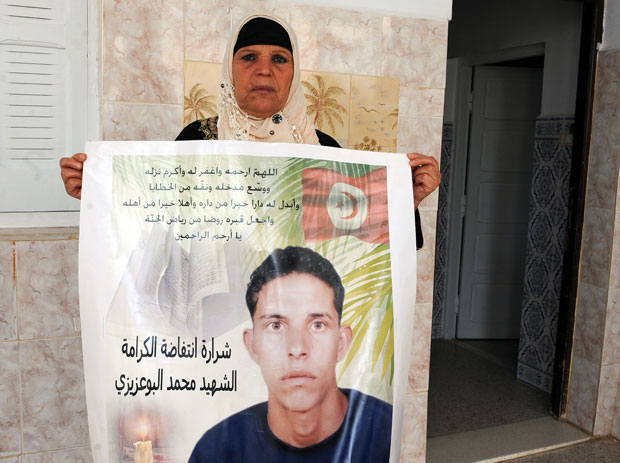 Manoubia Bouazizi, mãe de Mohamed Bouazizi, que passou a ser lembrado como motivador da revolta na Tunísia, segura faixa com uma foto do filho em foto de 15 de novembro de 2011 (Foto: Fetih Belaid/AFP)